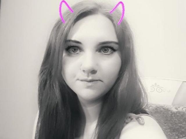 MaryCrystal, com cabelos longos e escuros, orelhas de gato cor-de-rosa e uma expressão séria em uma selfie em preto e branco. Seus olhos são grandes e ligeiramente voltados para cima. Ela tem um nariz pequeno..