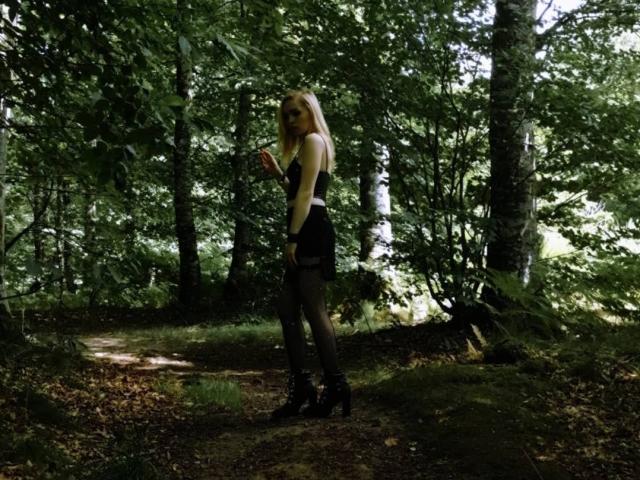 DreamArinna si trova in una foresta, indossa un abito nero, calze a rete e tacchi alti, tiene una sigaretta, ha i capelli biondi e uno sguardo seducente e sicuro di sé..