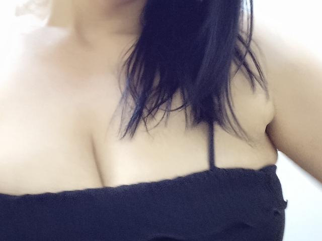 LizaRussell's tits are showing in a black strapless top, with her black hair partially covering her right shoulder. Her skin is light, and the image is slightly blurry.