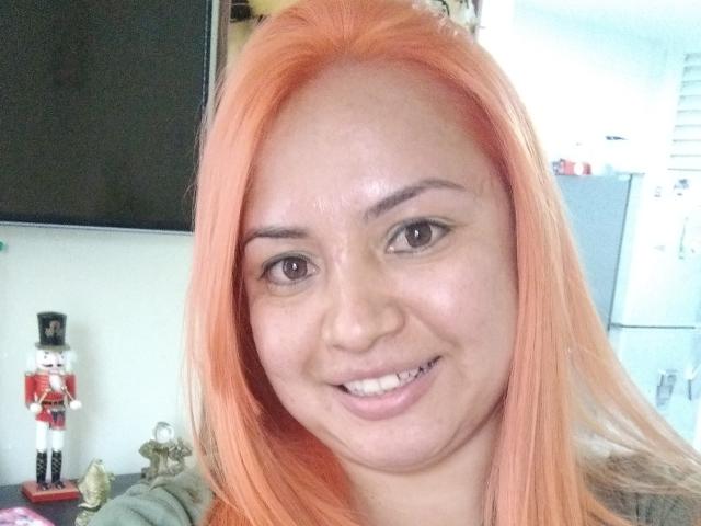 SweetSquirty ha i capelli biondi, gli occhi marroni e un sorriso carino. Si nota un piccolo spazio tra i suoi denti. Ha il seno piccolo e indossa una maglietta verde..