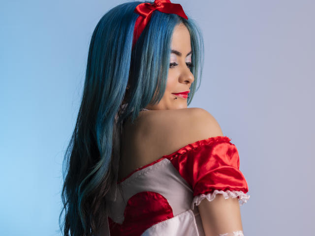 CandiceValo with blue hair, red ribbon, off-shoulder red and white dress, looking over shoulder, smiling, showing lip ring, sexy, cute, attractive.