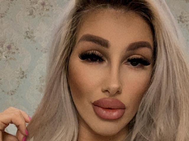 TanyaMonroe's pouty ass-kissing lips, full of glossy pink lipstick, stare with thick, long-ass eyelashes, and perfectly shaped eyebrows, surrounded by her platinum blonde hair.