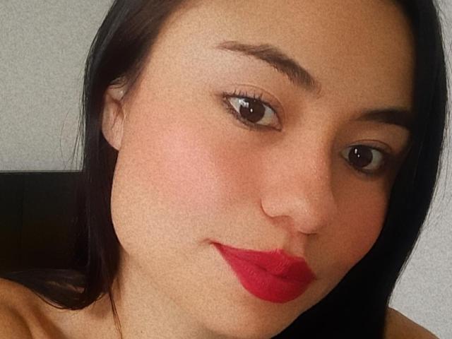 LolyFunX heeft een medium bruine huid, zwart steil haar, bruine ogen en rode lippenstift. Haar lichtrode wangen en subtiele glimlach dragen bij aan haar schattige, sexy uitstraling..