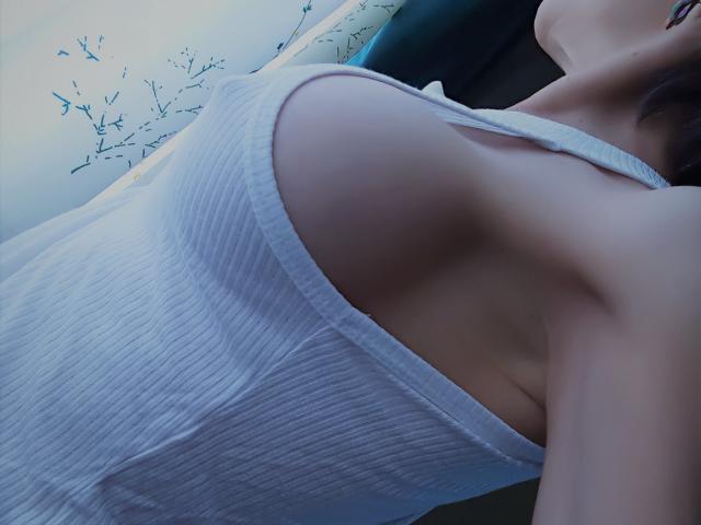 SharonLeidy's white ribbed tank top shows her large tits, with visible sideboob and armpit. Her head is tilted back, lips slightly parted, in a relaxed pose.