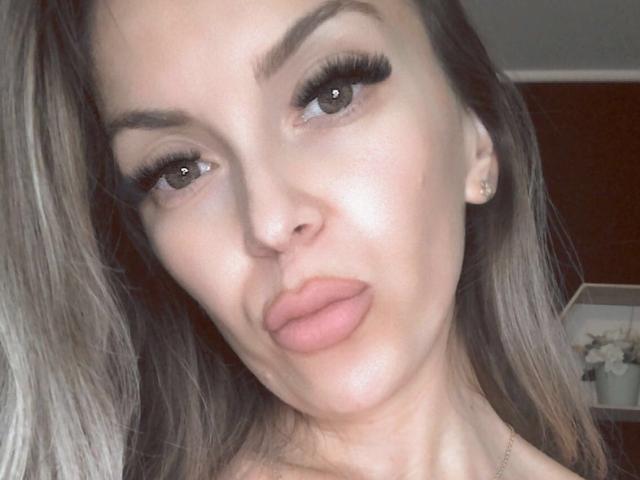 SophieDeee's face with pouty lips, long eyelashes, and brown eyes. She has light skin, brown hair, and a small nose. Her tits are not visible.