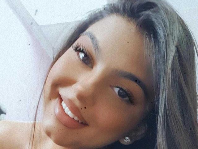 Il viso sorridente di Beckyte, con i suoi lunghi capelli grigiastri, gli occhi marroni e le piccole macchie scure sulle guance e sul labbro superiore, che mette in mostra i suoi graziosi denti bianchi e le labbra lucide..