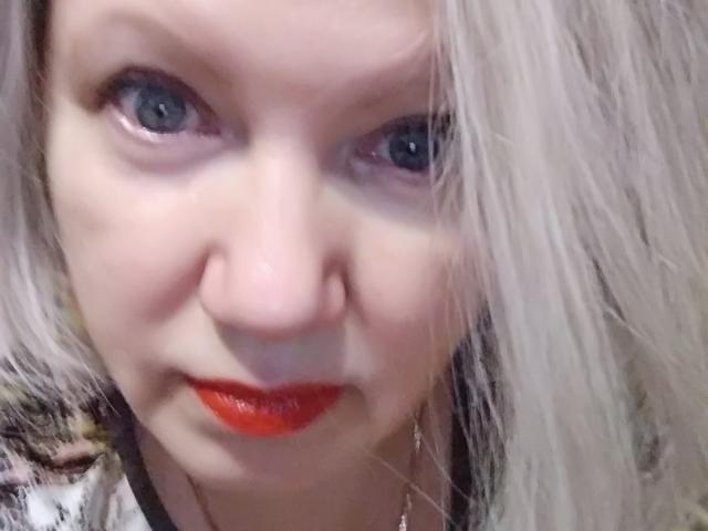 Agnnessa, met blauwe ogen, bleke huid en felrode lippenstift, heeft lang, rommelig, grijsblond haar dat de ene kant van haar gezicht bedekt. Haar neus is klein en haar uitdrukking is neutraal..