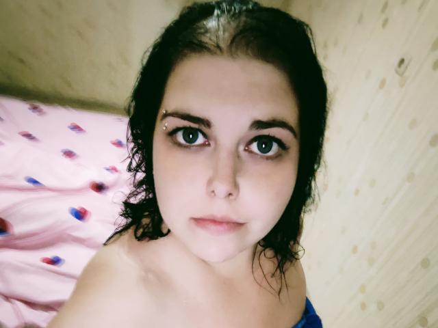 WhitteLotus a la peau pâle, les cheveux foncés et mouillés, les yeux bleus, un piercing au nez et un léger sourire. Elle est nue, avec de petites seins visibles. Son apparence est mignonne et innocente..