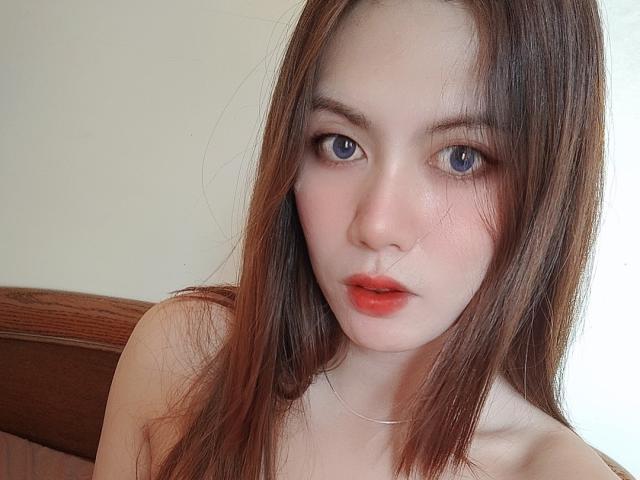 tsHOTLETITIA has pale skin, blue eyes, and brown hair, with red lipstick and a slight blush, looking directly at the camera with a neutral expression.