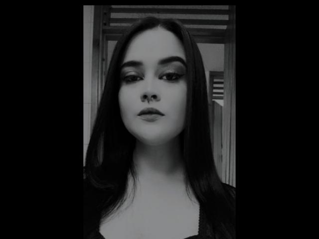 AbigailCroixX tem cabelo preto e liso, usa um piercing no nariz e está com delineador preto e sombra discreta, olhando diretamente para a câmera em um retrato em preto e branco..