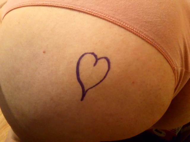 El trasero de LoveClo tiene un tatuaje en forma de corazón de color púrpura en la mejilla derecha, visible a través de la ropa interior rosa..