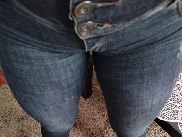 LuluFrancaise's ass in tight blue denim jeans with buttons, showing a slight gap and worn texture, standing on a carpeted floor.