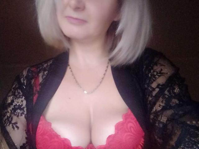 VAlica with blonde bob, wearing black lace robe, red lace bra showing her tits, and a silver necklace, smiling softly.