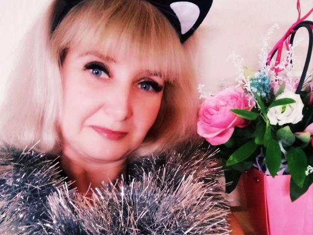 VAlica with blonde bob, cat ears, blue eyes, wearing shiny grey fur, smiling, pink rose bouquet in pink bag on right. Her tits are small and she's cute.