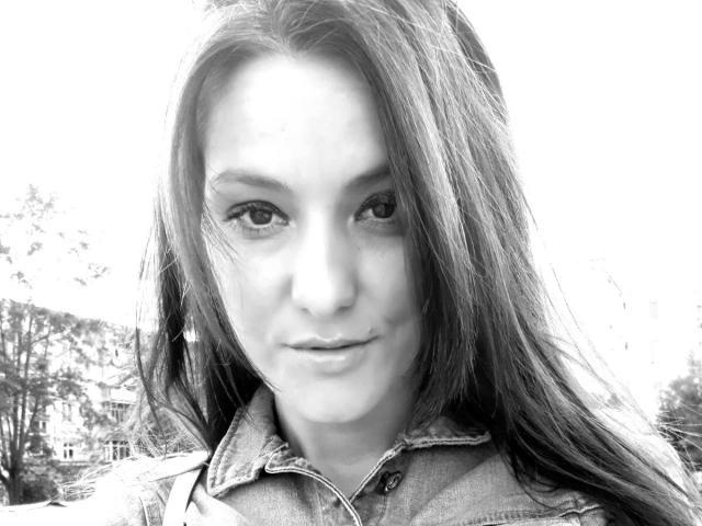 Zwart-wit selfie van JoliDanielle met lang, steil haar, gekleed in een denimjasje, met een lichte, zelfverzekerde glimlach. Haar ogen zijn gefocust en haar lippen zijn zachtjes gesloten..