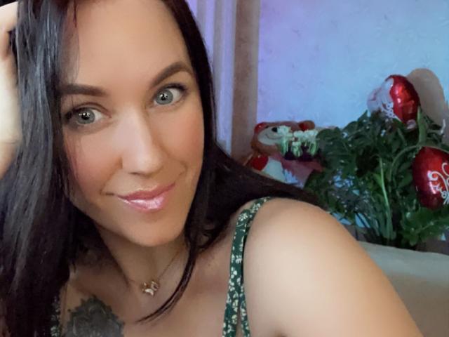 Misstyk a de beaux yeux verts, des cheveux noirs et un léger sourire avec des lèvres roses brillantes. Elle porte un haut vert à motifs, qui révèle un tatouage sur son épaule..