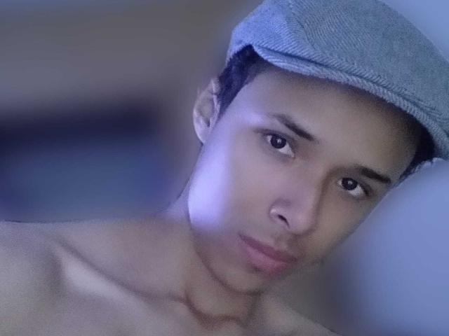 Hercolezz with a light blue flat cap, bare shoulders, and a serious expression, staring into the camera with a subtle, pouty look. Hercolezz's face is slightly blurred.