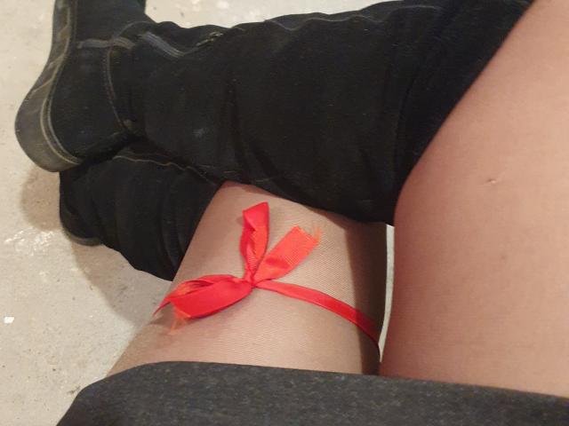 AnnaFock's thigh with a red ribbon tied around it, her leg bent with black boots on, showing pale skin. Boobless, assless, no visible pussy or tits.
