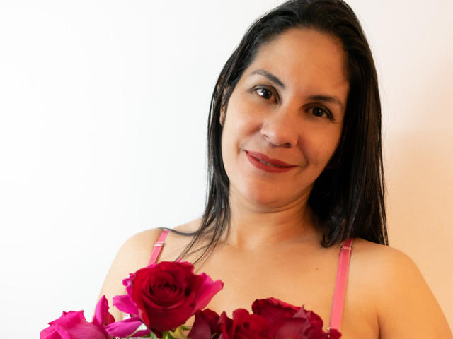 RoraimAnaggie a les cheveux brun foncé, un joli sourire, et porte un soutien-gorge rose avec des roses rouges recouvrant ses seins. Elle regarde l'appareil photo avec ses yeux marron..