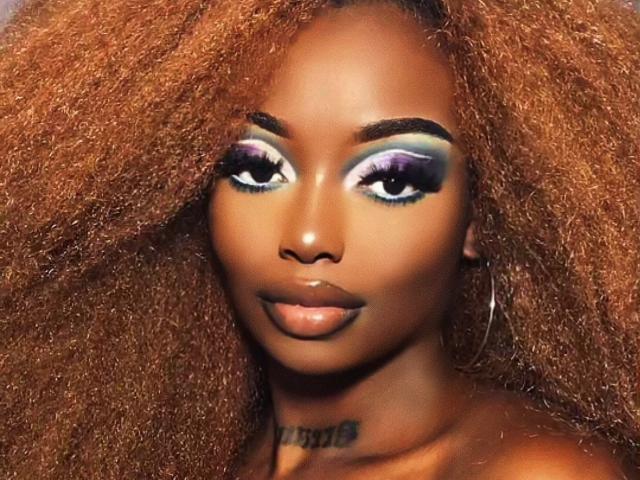 EbonyQueeny ha la pelle marrone scuro, i capelli ricci e arancioni, e il trucco per gli occhi è viola e verde, con lunghe ciglia. Guarda direttamente nella fotocamera con un sorriso appena accennato..