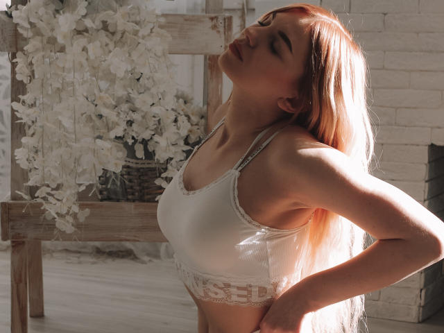 ScarletAmi, les yeux fermés, la tête penchée en arrière, portant un soutien-gorge en dentelle blanche, cheveux blonds clairs, éclairée par le soleil, les mains sur les hanches, lumière douce, détendue, dos légèrement arqué, petits seins..