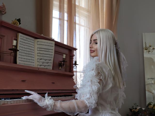PleasingAngel with long white hair, wearing a sheer white dress with ruffles and gloves, playing a pink piano, looking back with a smile. Her tits are visible through the dress.