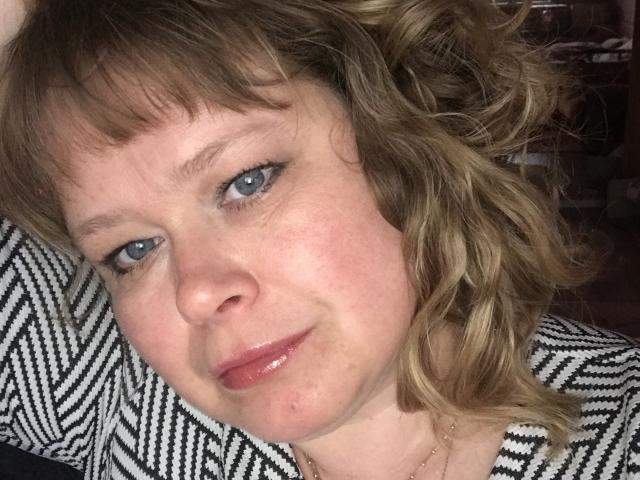 LarisaMaBelle hat welliges blondes Haar, blaue Augen und glänzende rosa Lippen. Sie trägt ein schwarz-weiß gemustertes Oberteil und hat eine leichte Rötung auf ihrer Wange. Sie lächelt leicht..