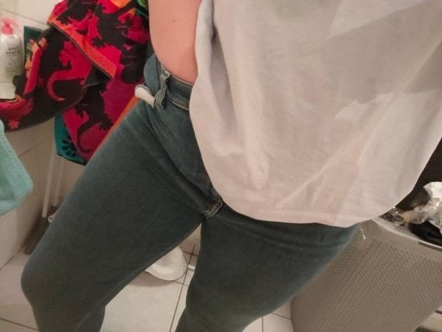 La maglietta grigia di FrancaiseLynne è leggermente bagnata, rivelando i suoi piccoli seni, e indossa dei jeans blu aderenti. La sua mano è in tasca. Ambientazione: bagno..