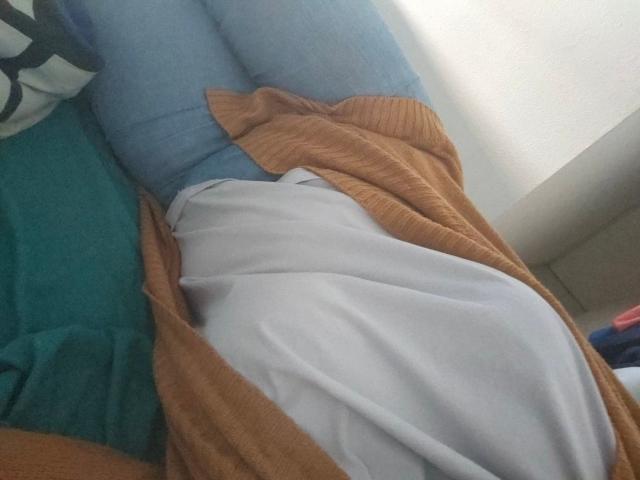 La parte inferiore del corpo di FrancaiseLynne, che indossa jeans blu, una camicia bianca e un cardigan di lana marrone, è parzialmente coperta, mostrando un sedere morbido e sinuoso, e una posa rilassata e informale..