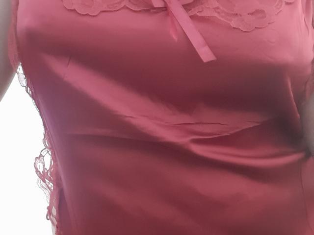 SolmaryHot's pink satin top with lace trim, showing subtle wrinkles and a small bow, highlighting her tits under the fabric. The image is a tight, upper-body shot.