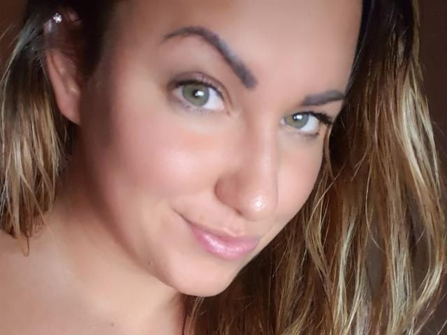 HotGirlVibe ha gli occhi verdi, un sorriso delicato e una piccola lentiggine sul naso. I suoi capelli castani sono sciolti e indossa una piccola clip all'orecchio. Il suo seno non è visibile..