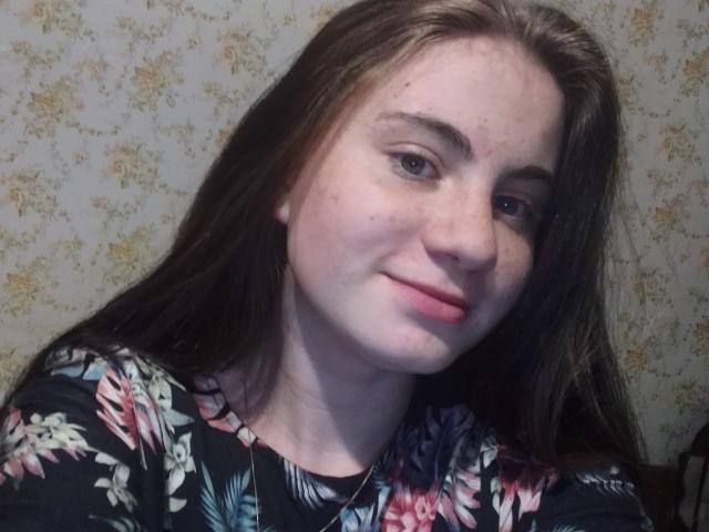 Solnushko69 ha la pelle chiara, i capelli castani, gli occhi azzurri e un leggero sorriso. Indossa una camicia a fiori con fiori rosa, bianchi e blu. Le sue natiche non sono visibili..