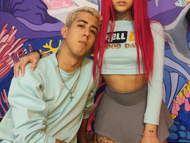 HardCoreSexy mit roten Haaren, kleinen Brüsten und einem Crop-Top steht neben HardCoreSexy mit blonden Haaren, einer Kreuzkette und einem hellblauen Pullover..