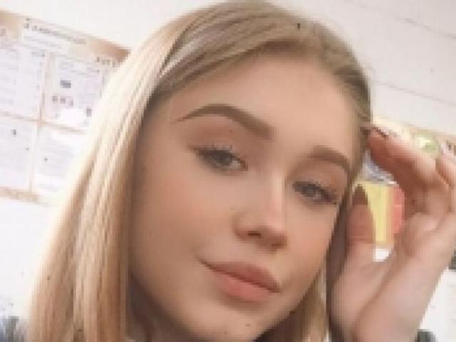 CrownofVice ha i capelli biondi, la pelle chiara e sta sorridendo con le labbra leggermente dischiuse. Sta toccando i capelli con la mano destra, mostrando il suo trucco delicato..