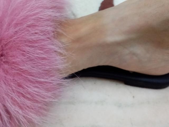 ASexyLady's pink furry butt, with a tan foot resting on top, showing a black strap, slightly out of focus.