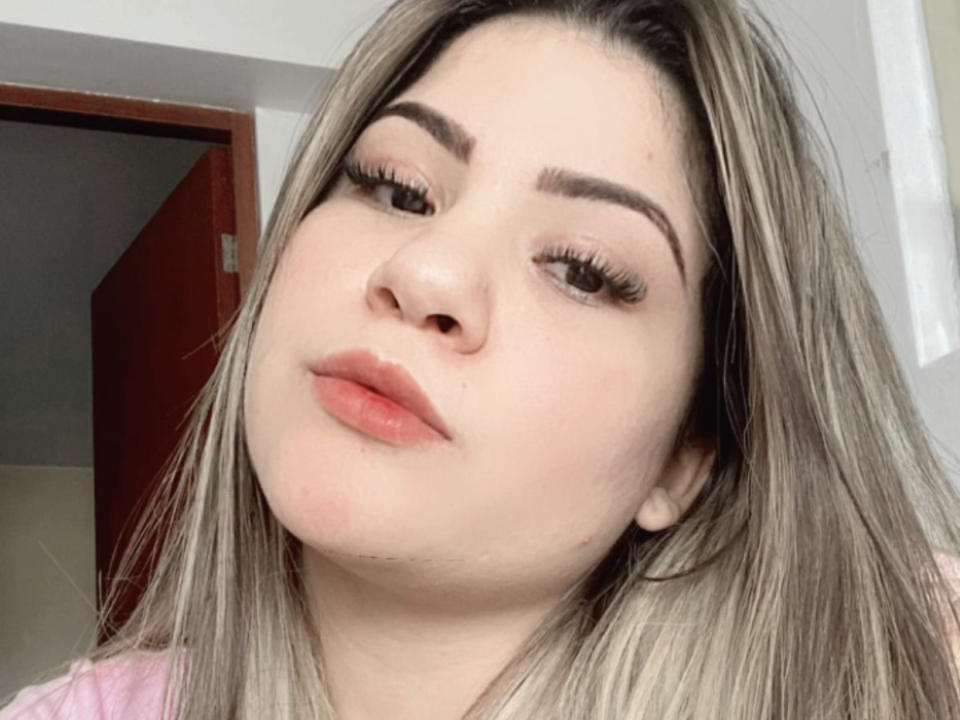 KeniaLove has light skin, full lips, and long, blonde hair with dark roots. She's looking down with thick, arched eyebrows and long, black eyelashes. Her tits are small.