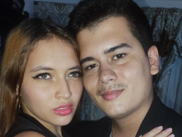 Jake und Megan haben ihre Gesichter nah beieinander, Jakes Gesicht mit seinem Schnurrbart und Megans Gesicht mit pinkfarbenem Lippenstift und schwarzem Eyeliner. Megan hat braunes Haar, Jake hat kurzes, dunkles Haar..