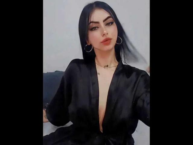 CristallEvans with black hair, hoop earrings, and a deep black satin robe, showing a bit of her tits, has a slight pout and a confident look.