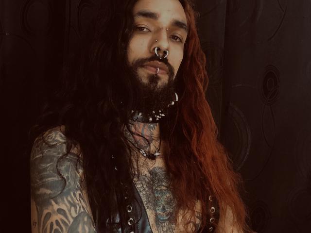 EscariotNEeva heeft lang rood haar, een volle baard, tatoeages die zijn borst en armen bedekken, een neusring en een lip piercing, en draagt een leren harnas..