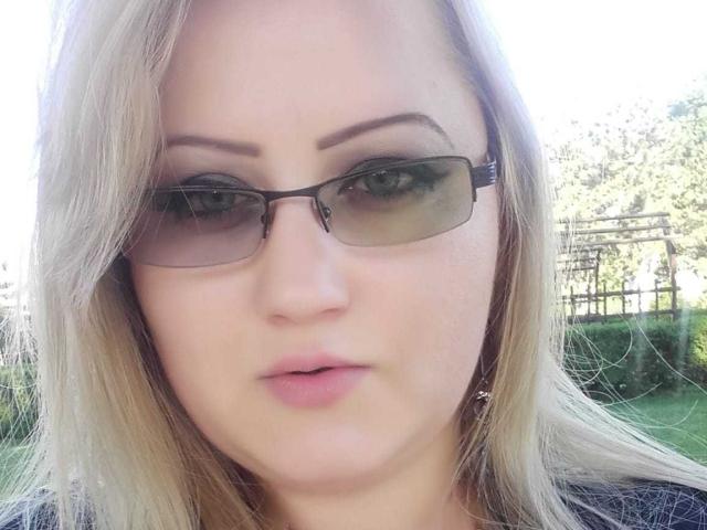 SeductiveBodyX with blonde hair, wearing black sunglasses, has a neutral expression, full pink lips, and light skin. She's looking directly at the camera, outdoors.