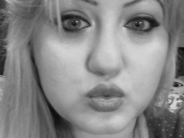 SeductiveBodyX has wide eyes with dark makeup, full lips, and a slightly pouty expression. She has light blonde hair and a fair complexion. Black and white photo.
