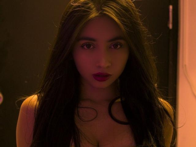 SakuraMiomi tiene el cabello largo, oscuro y húmedo, lápiz labial rojo y una expresión seria, con sus ojos marrones ligeramente abiertos. Lleva una blusa escotada que muestra sus pechos..