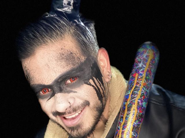 VisiI ha il viso dipinto di nero, occhi rossi e un nodo sulla testa con un motivo a teschio. Tiene per la spalla un pipistrello colorato e decorato, ed è sorridente. Il suo viso è pieno di lentiggini..