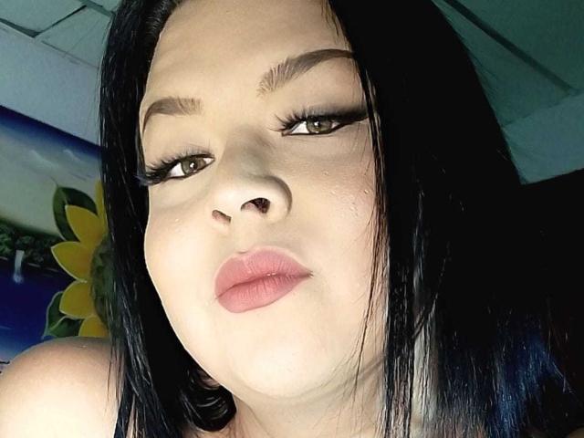 AlexaBigTs ha labbra rosa carnose, capelli neri lisci e sopracciglia folte. Sta guardando la fotocamera con un leggero sbuffo, con un trucco per gli occhi molto marcato. Il suo seno non è visibile..