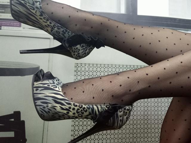 As pernas de BellaShannon, vestidas com collant pretas com bolinhas, e saltos altos, com um padrão de estampa de leopardo e laços pretos, estavam cruzadas no tornozelo..