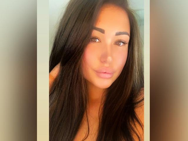 MelissaXCream a de longs cheveux bruns foncés, des sourcils épais, des yeux marrons et des lèvres roses. Sa peau est bronzée, et elle regarde directement l'appareil photo avec un léger sourire..