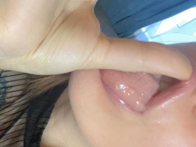 Misstyk's tongue is out, wet and glistening, with her index finger gently pressing against her upper lip. Her lips are slightly parted, showing a bit of pink inside.