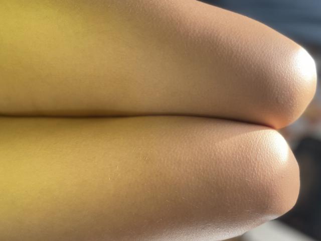 Misstyk's shiny, smooth, tan-colored butt cheeks are tightly pressed together in a close-up shot, highlighting their rounded, glistening surfaces under bright sunlight.