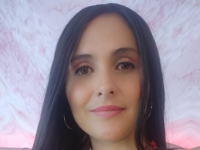 AmbeerBlack ha i capelli scuri, gli occhi marroni, il rossetto rosa e gli orecchini a cerchio, sorride dolcemente con un leggero rossore sulle guance. Guarda direttamente verso la fotocamera..