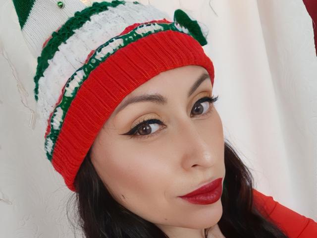 AliceRossi has red lipstick, dark eyeliner, and a red beanie with green and white stripes, looking at the camera with a slight smile. She has light skin and dark hair.